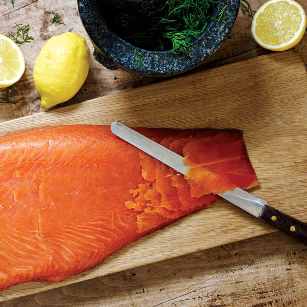 Premium Scottish oak-smoked salmon sliced on a wooden board with a filleting knife