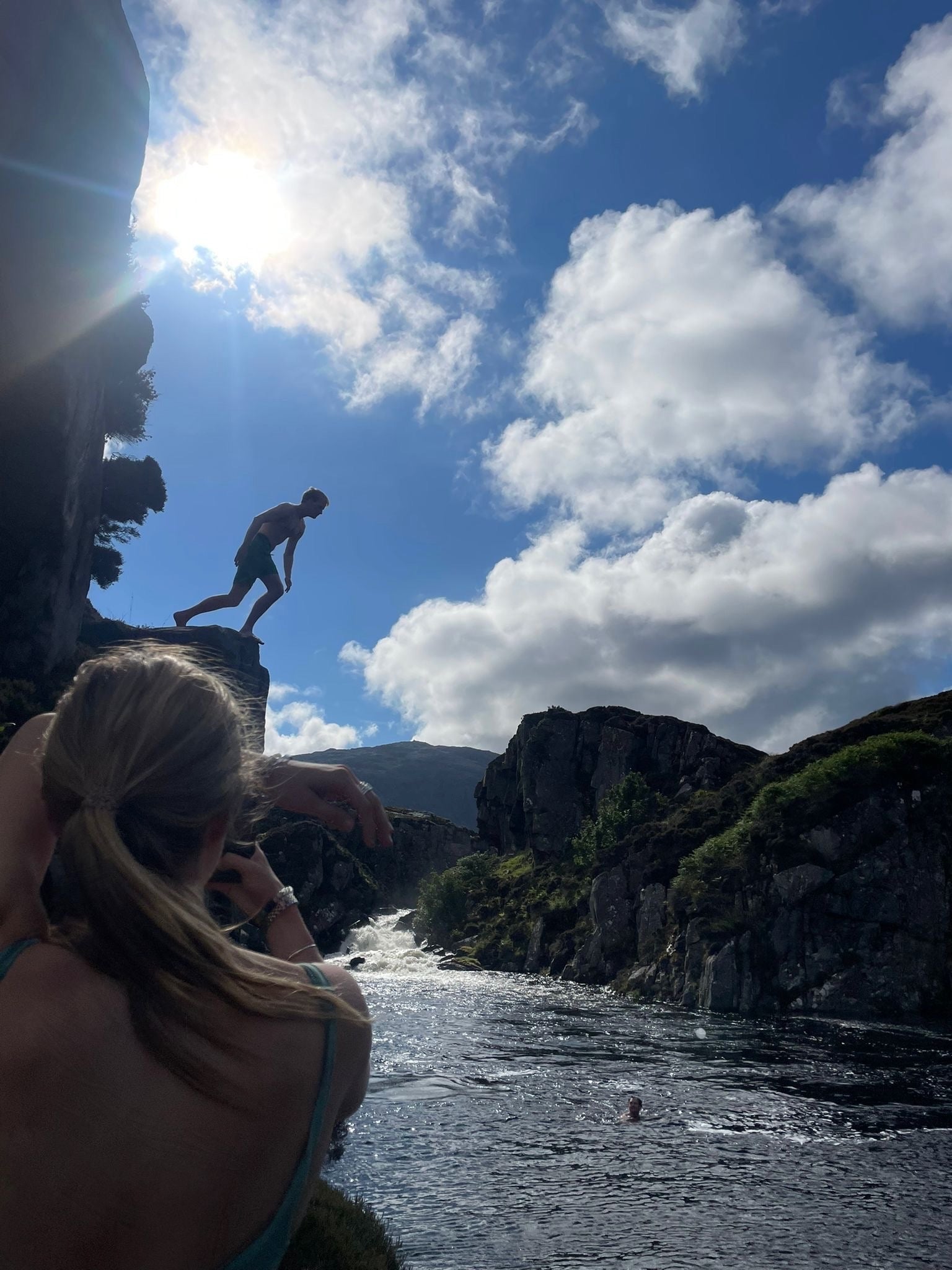 Boy jumping from the cliff at uig lodge, with view of the waterfall in the background
