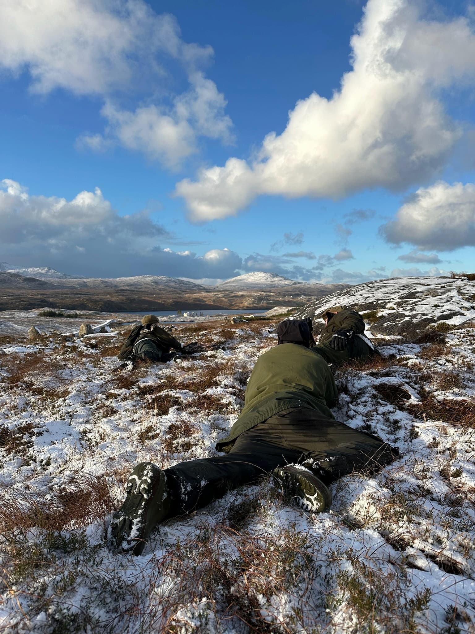 Man crawling through snow during a deer stalking trip in Scotland