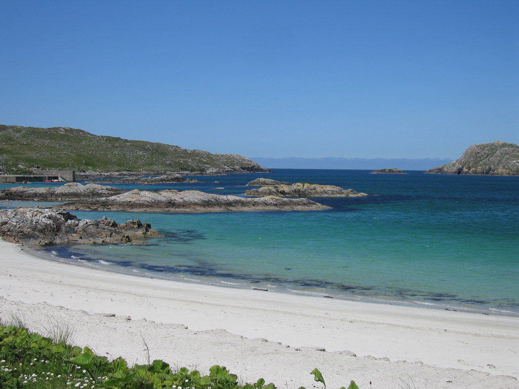 Beautiful reef beach with white sand and clear turquoise waters near Uig Lodge, highlighting the pristine coastal environment of the Isle of Lewis.