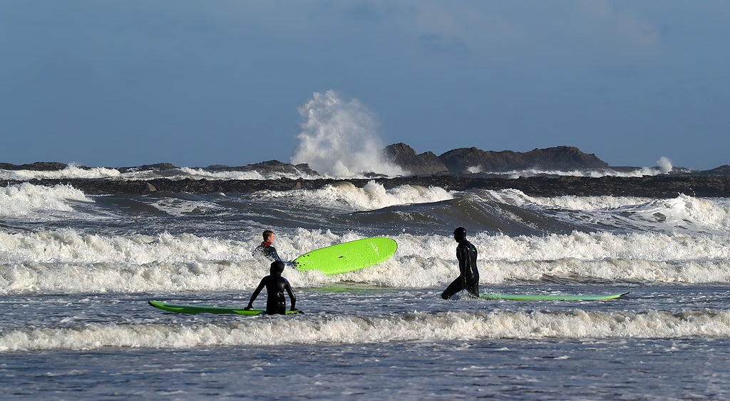 Surfers riding waves near Uig Lodge, enjoying the coastal scenery of the Isle of Lewis.