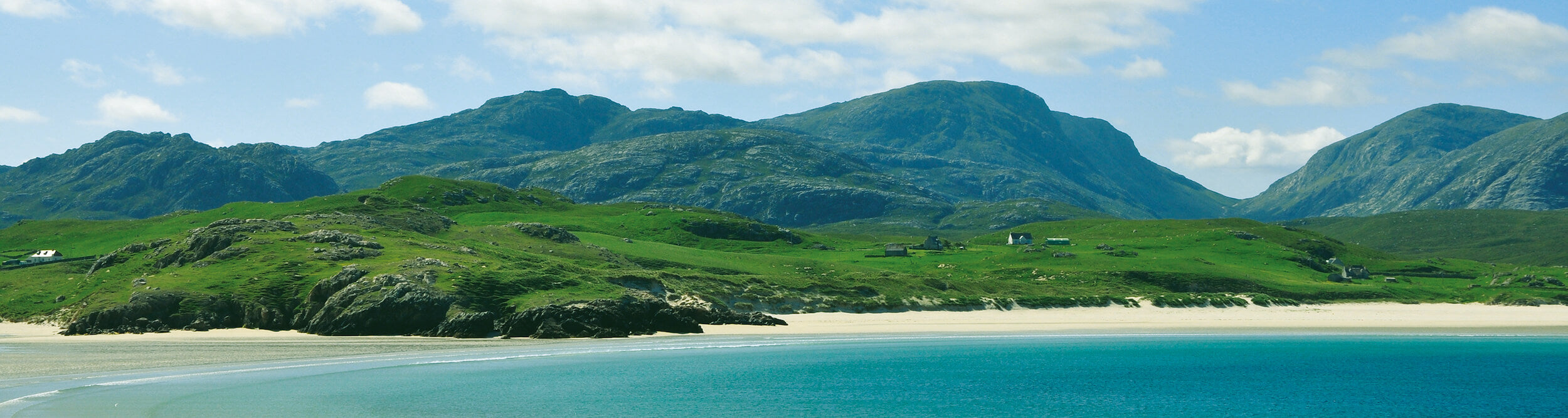 Uig Bay bathed in glorious sunshine with lush green mountains rising in the background