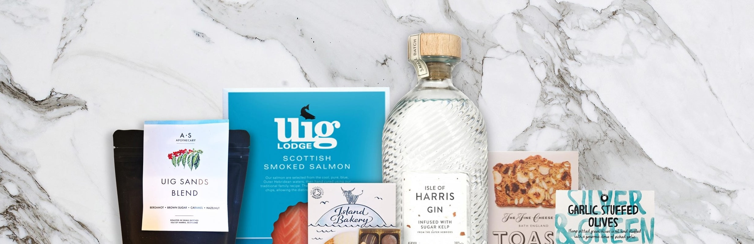 Collection of food products including a bottle of gin, a box of tea, and snacks on a marble surface.