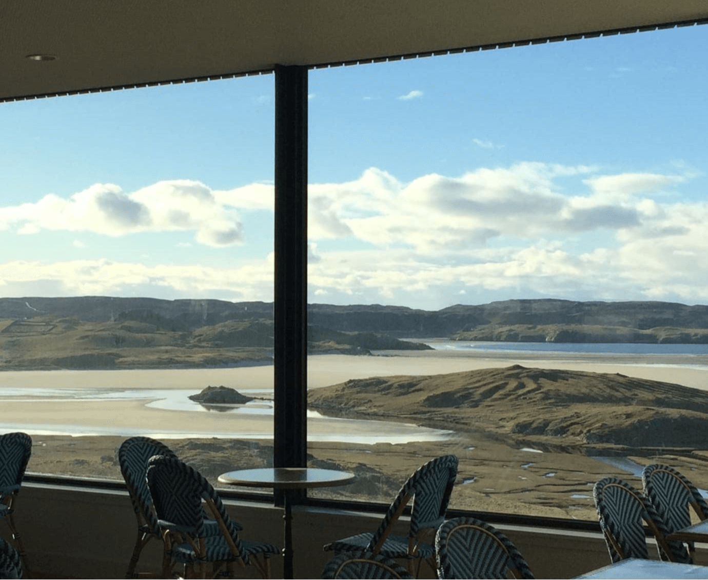 View from a room with large windows overlooking a scenic landscape with mountains and water.